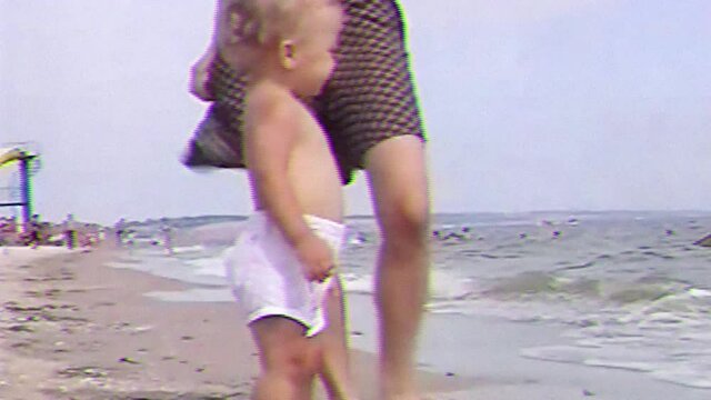 VHS footage from little happy boy run along the sand beach and smiling. Old home family movie of cute baby playing and enjoying on sea beach.