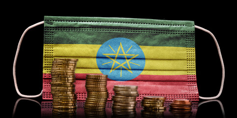 Medical mask with the flag of Ethiopia behind some shrinking stacks of various coins.(series)