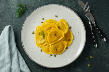 Homemade Pumpkin Ravioli with butter on a dark concrete background. Top view