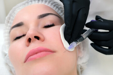 Cosmetic injections for skin rejuvenation. Cosmetologist injects a syringe into the skin