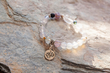 Silver pendant sanskrit om mineral beads bracelet on neutral natural rocky background