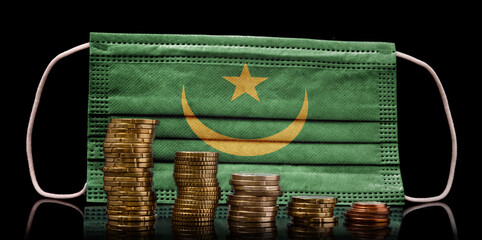 Medical mask with the flag of Mauritania behind some shrinking stacks of various coins.(series)