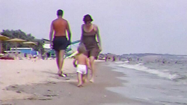 VHS footage from little happy boy run along the sand beach and smiling. Old home family movie of cute baby with mother playing and enjoying on sea beach.