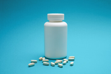 White bottle with pills isolated on blue background.