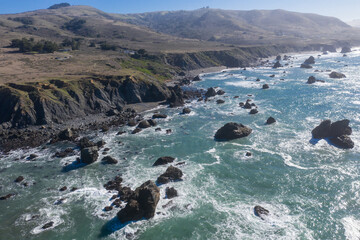 Fototapeta premium The Pacific Ocean washes against the rugged shoreline of northern California on a beautiful winter day. The scenic Pacific Coast Highway runs along much of the edge of California.