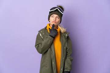Skier Russian girl with snowboarding glasses isolated on purple background having doubts while looking up