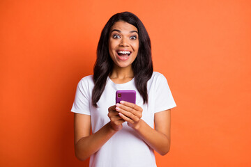 Photo of excited crazy lady hold cellphone open mouth wear white t-shirt isolated orange color background