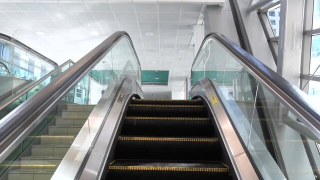 Moving up the escalator with glass sides and metal steps in the metro station coming to the platform