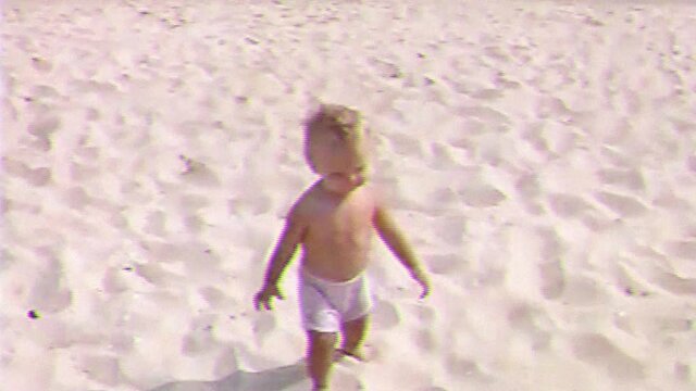 VHS footage from little happy boy run along the sand beach and smiling. Old home family movie of cute baby with mother playing and enjoying on sea beach.