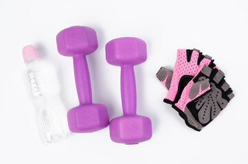 sports gloves, pair of purple dumbbells and and bottle of water on a white background