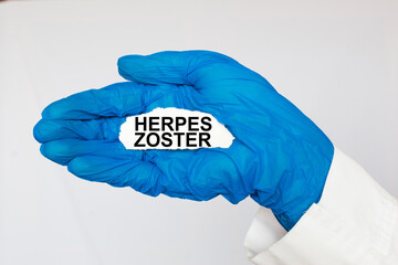 The doctor's blue - gloved hands show the word HERPES ZOSTER - . a gloved hand on a white background. Medical concept. the medicine