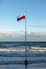 the Polish flag against the background of blue sky and blue sea