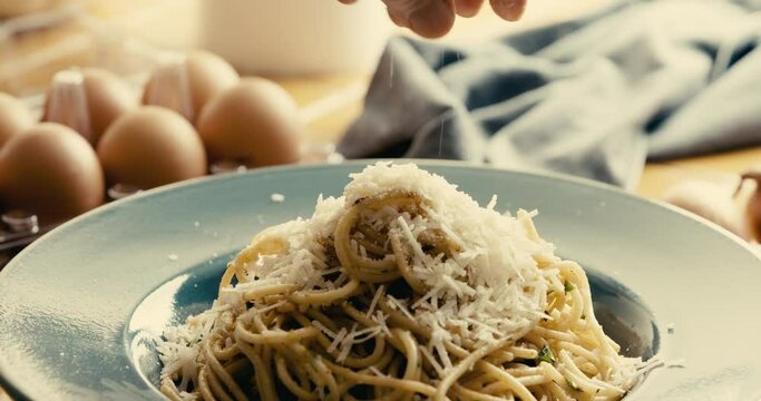 Sprinkling  parmesan cheese on spaghetti
