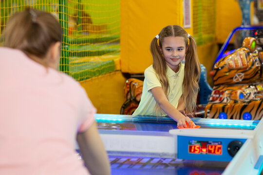 Family Recreation Concept. Happy Teen Girl Playing Air Hockey With Her Mother At Kids Entertainment Center