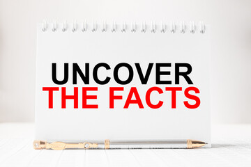 Fototapeta premium Notepad with inscriptions UNCOVER THE FACTS on a white background. business concept.