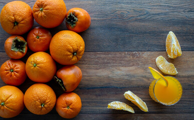 Food background. Orange, tangerine, persimmon and orange juice glass on the wooden table