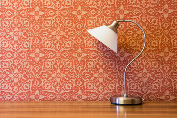 Beautiful table lamp on a wooden table against a background of a red wall