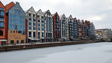 Beautiful colorful townhouses on the banks of the frozen Motlawa River in Gdansk, Poland