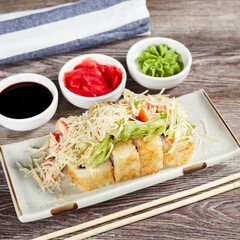 japanese sushi rolls in a rectangular plate on a light wooden table