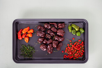 Two plates of various hot chili peppers (Habanero, Chiltepin and Jolokia) on bright gray background. Top view with copy space.