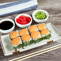 japanese sushi rolls in a rectangular plate on a light wooden table