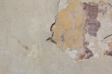 An old beige wall with broken plaster.
