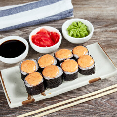 japanese sushi rolls in a rectangular plate on a light wooden table