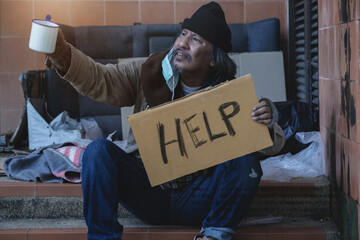 Homeless begging man with a medical mask holding a cup to ask for donation, the words 