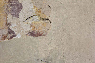 An old beige wall with broken plaster.