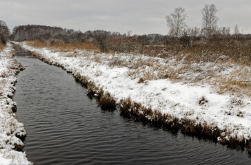 Winter landscape of wetland meadows Natura 2000 area with water canal. Snowy landscape. Bagno Pulwy, Rzasnik, Poland.