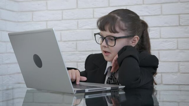 Happy little businesswoman. A little girl at the computer screams with joy.