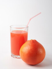 Fresh grapefruits and a glass of grapefruit juice on a white wooden background with a copy space. Close-up.