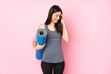 Fototapeta premium Young caucasian woman with mat isolated on pink background laughing