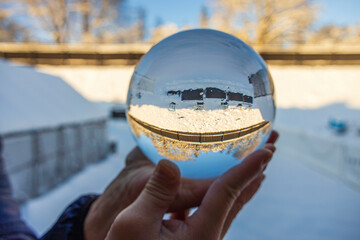 Close up macro view of hand holding crystal ball with inverted  image of winter natural landscape. Sweden.