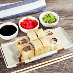 japanese sushi rolls in a rectangular plate on a light wooden table