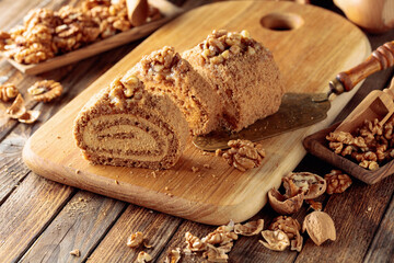 Walnut cake, nuts and wooden kitchen utensils on a wooden table.