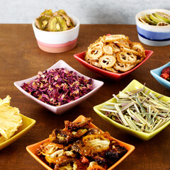 Colorful bowls with dehydrated food and herbs. Different dry vegetables and fruits on wooden table.