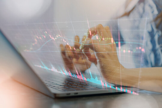 ノートPCを操作する女性の手と株価チャートの合成写真