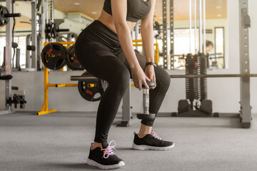 Close up fitness woman in sportswear doing squat exercise and holding dumbbells at gym