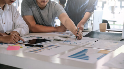 Young Asian businessman are meeting at working and pointing to analyzing charts and graphs.