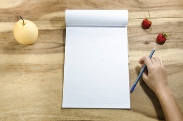 hand with pencil and paper on wooden table