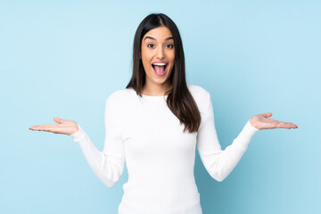 Young caucasian woman isolated on blue background with shocked facial expression