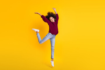 Full size photo of cheerful dark skin person jumping have fun wear sweater isolated on yellow color...