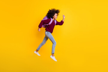 Fototapeta na wymiar Full body profile photo of wavy dark skin girl running carry rucksack wear sweater isolated on yellow color background