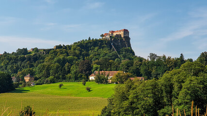Fototapeta na wymiar Riegersburg castle in Austria towering above the area. There are mais crops ripening on the field in front. Clear blue sky above the castle. The massive fortress was build on the rock. Middle ages