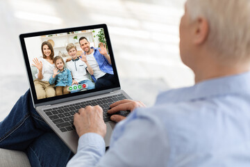 Elderly woman using laptop to speak to her children and grandkids online from home, making video...