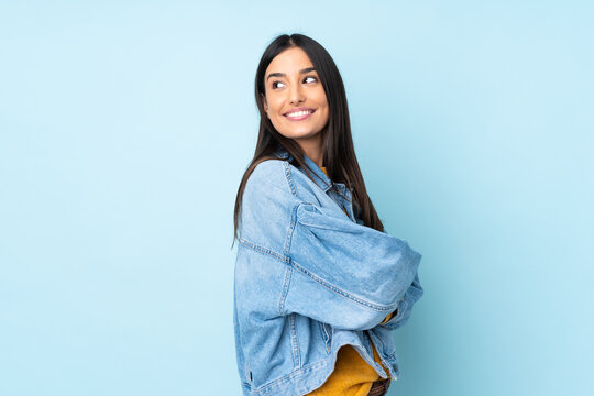 Young caucasian woman isolated on blue background looking to the side and smiling