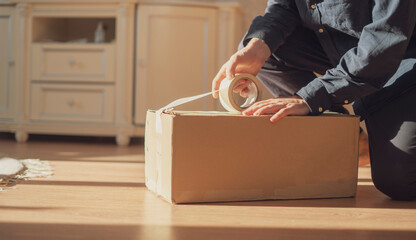person holding a tape and box to pack the cardboard, send and deliver shipping