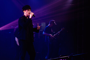 Singer holding a microphone stand and performing on stage. Rock concert show set up.