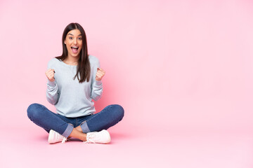 Young caucasian woman isolated on pink background celebrating a victory in winner position